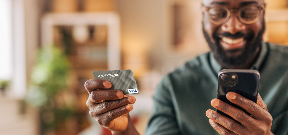 Man holding up Tompkins Credit card